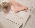 May include: A wedding invitation card with gold script that reads "To My Maid of Honor on My Wedding Day" is paired with a pink envelope. A small velvet ring box with two rings and a wine glass are also in the image.