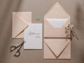 May include: A white card with black calligraphy that reads "Dear Katherine, will you be my bridesmaid?"  The card is surrounded by three pink envelopes and a small green wax seal.