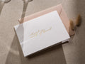 May include: White card with gold lettering that says "Will you be my maid of honor?"