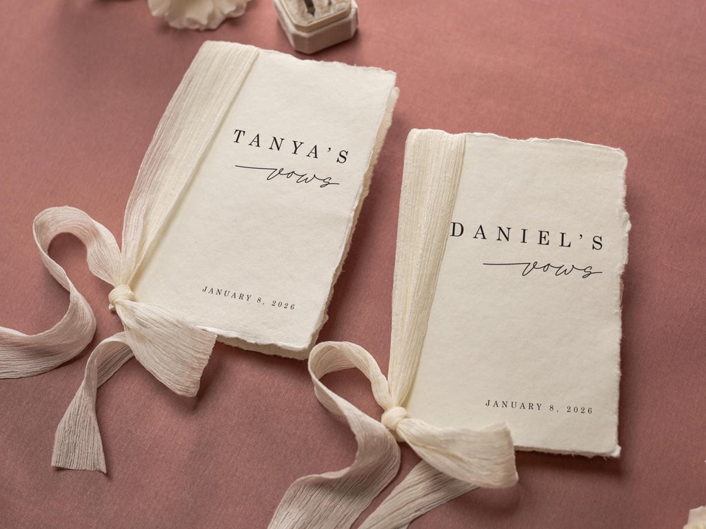 May include: Two vow books with deckled edges, tied with cream-colored ribbons. The text "Tanya's vows" and "Daniel's vows" are printed in black script, along with the date January 8, 2026. The background is a muted rose color.